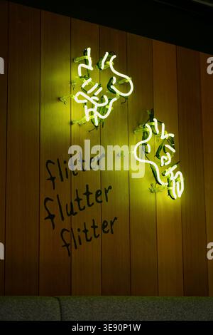 Grünes Neonschild Mit Abstrakter Typografie Mit Der Aufschrift Flitter Flatter, Montiert Auf Holzpaneelwand Stockfoto
