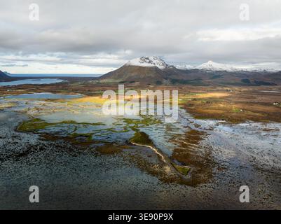 Aus der Vogelperspektive der Insel Andoya mit weiten Feuchtgebieten, Küstensümpfen und schneebedeckten Berggipfeln unter einem dramatischen bewölkten Himmel Andoy, Nordland, Nor Stockfoto