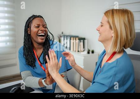 Glückliche Mediziner lachen und geben High-Five in der Klinik Stockfoto