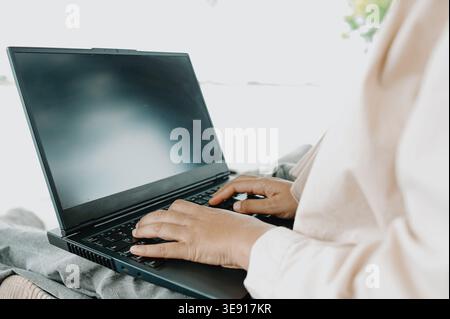 Muslimische Frau, die Remote mit einem Laptop arbeitet, auf Rocks in Nature, Outdoor Freelance Lifestyle, Digital Nomad, Unternehmensproduktivität in einer landschaftlich reizvollen Umgebung Stockfoto