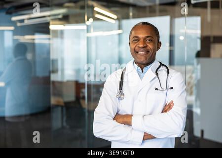 Erfahrener Gesundheitsdienstleister, der stolz mit gekreuzten Armen und einem Stethoskop steht, verkörpert Professionalität und Pflege in einer modernen medizinischen Praxis Stockfoto