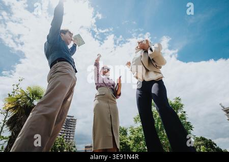Geschäftskollegen feiern im Freien mit erhobenen Armen in einem Stadtpark Erfolg Stockfoto