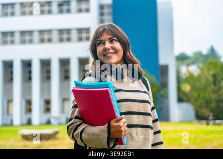 Glückliche junge Studentin, die auf dem Campus läuft Stockfoto