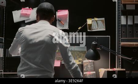 Inspektor analysiert Beweise an Bord im Archivraum, liest Zeugenaussagen. Privatbüro, das verdächtige Fotos ansieht und Strafregister im Ermittlungsbüro überprüft. Stockfoto