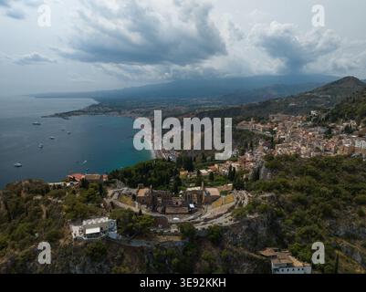 Aus der Vogelperspektive des antiken Theaters von Taormina mit Blick auf das Ionische Meer und die Stadt unter einem dramatischen bewölkten Himmel Taormina, Sizilien, Italien. Stockfoto