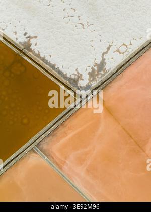 Aus der Vogelperspektive der farbenfrohen Salinen mit geometrischen Mustern aus weißen Salzkrusten und getöntem Wasser in Marsala, Sizilien, Italien. Stockfoto