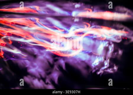 Ätherische Lichtmalerei mit lila und rot leuchtenden Pfaden, die durch dunklen Rauch hindurch führen Stockfoto