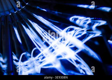 Verworrenes Netz von hellen blauen Lichtlinien, die auf einer komplexen kristallinen Glasoberfläche reflektiert werden Stockfoto