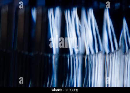 Abstrakte vertikale blaue und weiße, unscharfe Linien, die durch geripptes Glas Licht ähneln Stockfoto