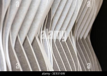 Abstraktes wellenförmiges graues und weißes Muster, das ein dynamisches architektonisches Design bildet. Glatte Kurven für einen modernen, strukturierten Hintergrund. Soundpanels Stockfoto
