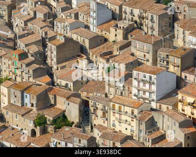 Blick aus der Vogelperspektive auf die dicht gepackten Steinhäuser und Terrakottadächer der historischen Stadt Gangi, Sizilien, Italien. Stockfoto