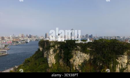 Aus der Vogelperspektive des weißen Leuchtturms Kaohsiung auf einer felsigen Klippe mit Blick auf den Hafen und die Skyline der Stadt Yicheng Village, Kaohsiung City, Taiwan. Stockfoto