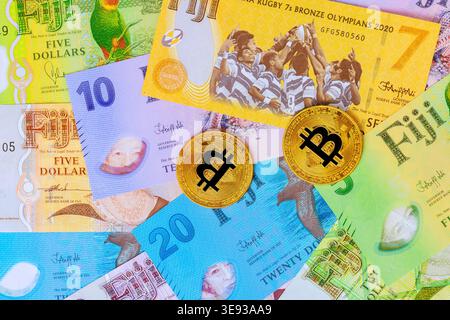 Fidschi-Bargeld-Banknoten, Bitcoin-Münzen sind auf dem Tisch verteilt verschiedene Wertgestaltungen der Währung. Stockfoto