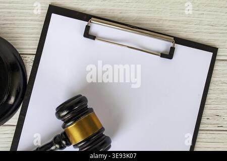 Draufsicht einer leeren Zwischenablage aus weißem Papier mit anpassbarem Platz für Text und einem Gavel daneben Stockfoto