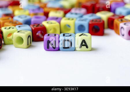 NDA-Text zu mehrfarbigen Würfeln , die die Geheimhaltungsvereinbarung darstellen . Erhaltungskonzept Stockfoto