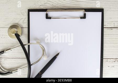 Draufsicht einer leeren Zwischenablage mit einem Blatt weißem Papier und einem Arzt-Stethoskop. Konzept für Kopierbereich Stockfoto