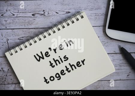Wir sind in diesem zusammen Text auf Notizblock mit Telefon und Holzschreibtisch Hintergrund. Teamwork-Konzept Stockfoto
