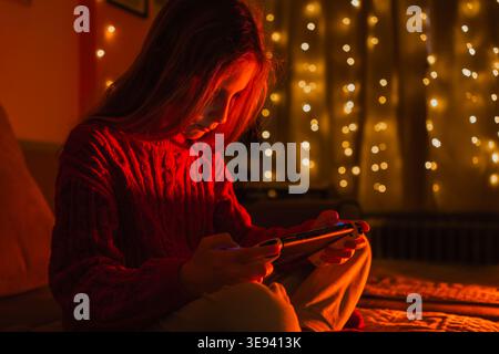 Mädchen, das in einem dunklen Raum mit warmen orangefarbenen Lichtern spielt Stockfoto