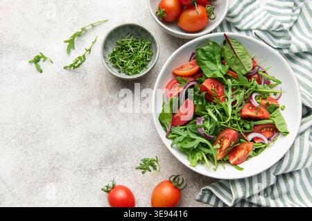 Gesunde vegane Mahlzeit mit frischen Tomaten, Rucola, Spinat und roten Zwiebeln Stockfoto