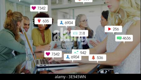 Arbeitende blonde Frau, die auf einem Laptop am Meeting-Tisch schreibt, in ärmelloser Oberseite, soziale Symbole, Kopierraum Stockfoto