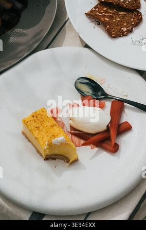 Dessertteller glänzt mit Eleganz. Gelber Vanillepudding trifft auf knusprige, orange gefärbte Karotten. Weiches Eiweiß liegt neben den Karotten. Löffel liegt neben dem d Stockfoto
