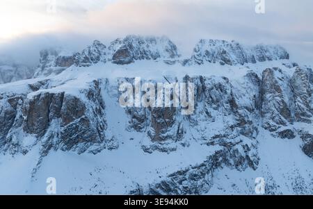 Aus der Vogelperspektive der verschneiten Berggipfel der Dolomiten, die im Winter teilweise von Wolken und Nebel bedeckt sind, in Wolkenstein in Gröden, Trentino-Südtirol, Stockfoto