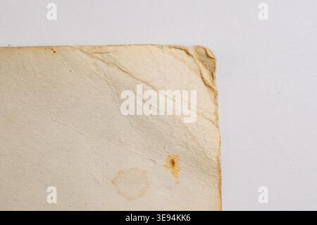 Nahaufnahme einer Ecke aus altem, strukturiertem Papier mit sichtbaren Flecken und ausgefransten Kanten, die den Vintage-Charakter und die Geschichte hervorheben Stockfoto