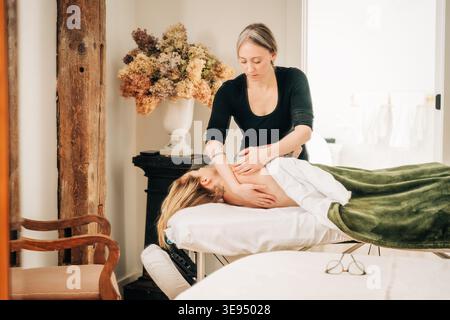 Therapeut massiert die Schulter des Patienten zur Nacken- und Stresslinderung Stockfoto