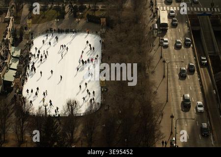 Die Menschen laufen auf einer Eisbahn neben einer befahrenen Straße mit fahrenden Fahrzeugen. Stockfoto