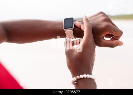 Zugeschnittene Nahaufnahme eines Mannes, der eine Smartwatch am Handgelenk vor einem weichen Hintergrund im Freien justiert. Moderne Technologie, Fitness-Tracking, tragbare Geräte Stockfoto