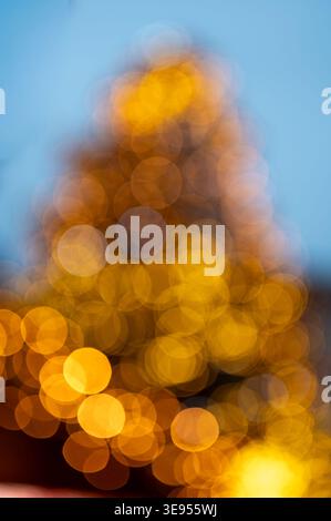 Nahaufnahme von Weihnachtsbaumlichtern mit defokussiertem Hintergrund, der weiche Bokeh-Kreise erzeugt warme glühende Weihnachtsbeleuchtung, festliche Winteratmosphäre ab Stockfoto