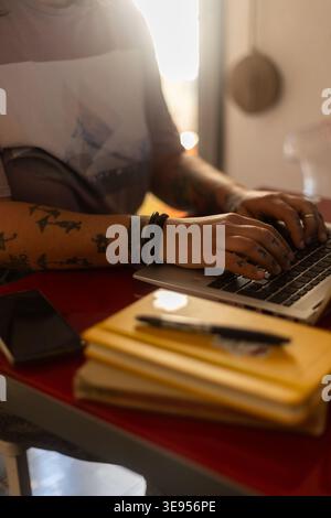 Nahaufnahme von tätowierten Händen, die auf der Laptop-Tastatur tippen, für kreative Freiberufler und ein alternatives Konzept für Fernarbeit Stockfoto