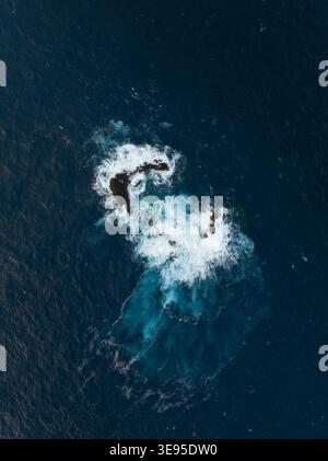 Luftaufnahme von Wellen, die gegen vulkanische Felsformationen im tiefblauen Atlantik in Porto Moniz, Madeira, Portugal, prallen. Stockfoto