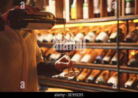 Frau, die Rotwein in den gemütlichen Keller gießt Stockfoto