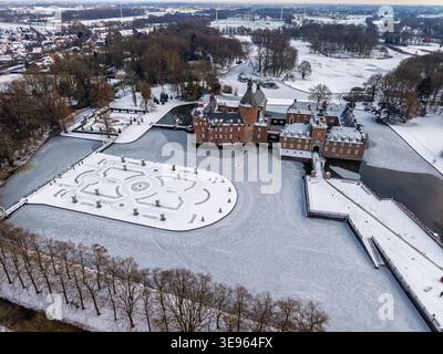 Luftaufnahme von Schloss Anholt im Winter. Die mittelalterliche Ziegelfestung ist von einem gefrorenen Graben und schneebedeckten formellen Gärten umgeben. Ein atemberaubendes Hallo Stockfoto