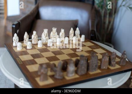 Holzschachbrett mit mittelalterlichen Stücken in gemütlicher Einrichtung. Konzept von Strategie, Entscheidungsfindung, Führung und intellektuellem Spiel. Stockfoto