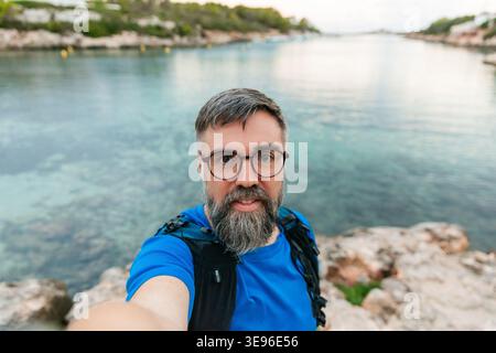 Ein Mann, der Selfie macht und auf menorca entlang der Küste läuft Stockfoto