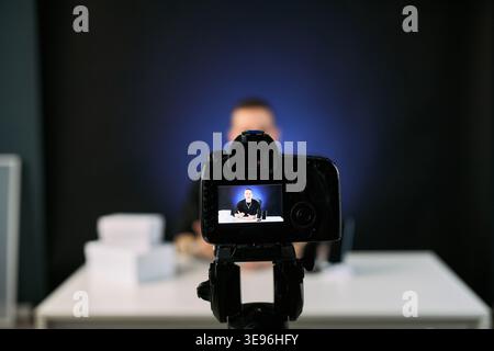 Junger Erwachsener, der hinter Digitalkameras Video-Blogs aufnimmt, Inhalte für Online-Publikum streamt und Marketing für kreative Künstler. Nützlich für Influencer-Werbung, soziale Medien und Fernübertragung Stockfoto
