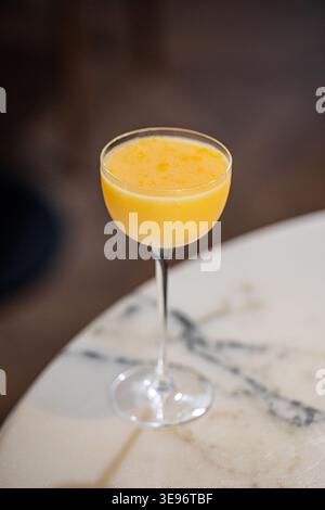 Orangencocktail im Coupé-Glas auf Marmortisch Stockfoto