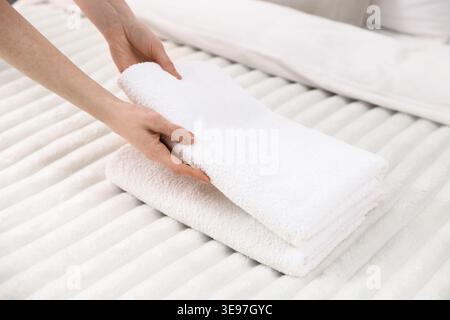 Frau, die Handtücher aus dem Bett nimmt, Nahaufnahme Stockfoto