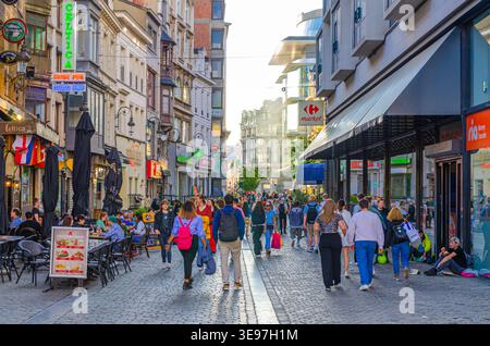 Brüssel, Belgien, 7. Juli 2023: Menschenmassen Touristen gehen die Fußgängerzone mit vielen Geschäften, Geschäften, mittelalterlichen Häusern und Gebäuden entlang Stockfoto