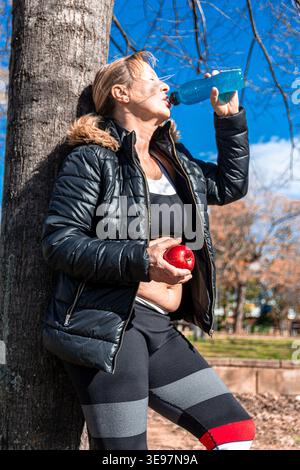 Seniorin, die nach dem Fitness-Training im Freien hydriert Stockfoto