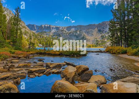 Klares Wasser, das über Felsbrocken in einem felsigen Bach fließt, führt zu einem türkisfarbenen Bergsee, der von zerklüfteten Bergen in Mammoth Lakes, Kalifornien, umgeben ist. Stockfoto
