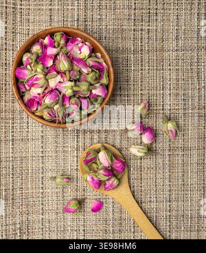 Trockene Rosenknospen, Rosenblüten für rosa Blumentee, getrocknete persische Rosenknospen, Rosenknospen strukturierte Blumen auf natürlichem hölzernem rustikalen Hintergrund Stockfoto