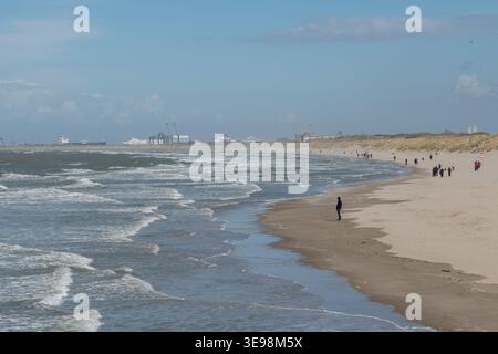Blankenberge, Belgien - 5. April 2026: Breiter Sandstrand mit Nordseewellen und Menschen, die unter bewölktem Himmel entlang der Küste spazieren. Reisenachrichten, Tourismus Stockfoto
