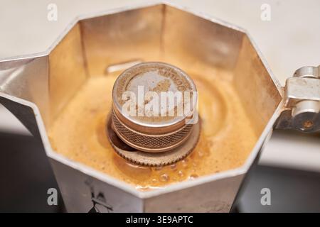 Nahaufnahme der reichhaltigen, goldenen Crema, die in einem klassischen Mokakopf mit Herdplatte sprudelt und einen authentischen und warmen Morgenkaffee festmacht. Stockfoto