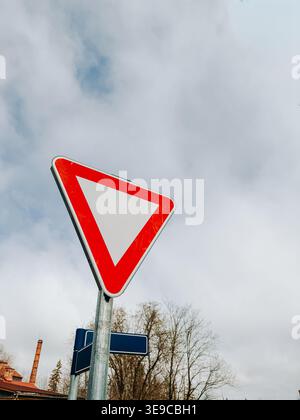 Riga, Lettland - 17. April 2026: Niedrigwinkelansicht eines rot-weißen Verkehrsschildes vor einem bewölkten Himmel. Ideal für Konzepte der Straßenverkehrssicherheit, richtig o Stockfoto