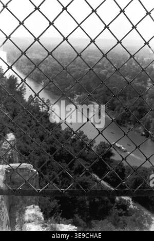 Historischer Archivblick von Slavyanogorsk (heute Sviatohirsk) aus dem Jahr 1956 mit Blick auf das malerische Tal des Siwerskyi Donets. Die Szene fängt eine Hochwinkelperspektive ein, die durch einen Drahtzaun aus Diamantgewebe hinunterblickt und kleine Ruderboote enthüllt, die durch das ruhige Wasser inmitten von dichten Sommerwäldern navigieren. Diese nostalgische Landschaft aus der Mitte des zwanzigsten Jahrhunderts zeigt die natürliche Schönheit und die Outdoor-Freizeitkultur der Sowjetzeit, wobei die historische Umgebung und das topografische Erbe der Region erhalten bleiben und den friedlichen Donbass widerspiegeln. Stockfoto