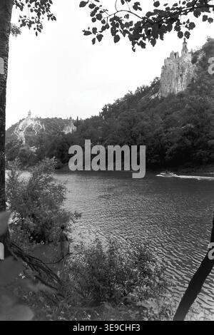 Historischer Archivblick von Slavyanogorsk (heute Sviatohirsk) aus dem Jahr 1956 mit Blick auf den malerischen Fluss Siwerskyi Donets, der von dunklen Baumsilhouetten eingerahmt wird. Die Szene fängt kleine Ruderboote und eine Passagier-Flussbahn auf dem Wasser ein, während die majestätische Kreidekirche St. Nikolaus auf der Klippe im Hintergrund aufsteigt. Diese nostalgische Landschaft aus der Mitte des zwanzigsten Jahrhunderts hebt die natürliche Schönheit und das architektonische Erbe der Sowjetzeit hervor und bewahrt die historische Umgebung der Region und spiegelt den friedlichen Donbass wider. Stockfoto