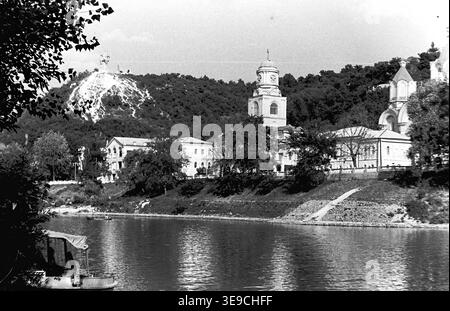 Historischer Blick aus dem Jahr 1956 auf Slavyanogorsk (heute Sviatohirsk), der das herrliche architektonische Erbe entlang des Siwerskyi Donets-Flusses zeigt. Die Szene zeigt die historischen Gebäude von Svyatogorsk Lavra, einschließlich der Pokrowskaja Kirche mit ihrem Uhrenturm, die sich vor dem bewaldeten Kreideberg und dem Artem-Denkmal befindet. Diese nostalgische Landschaft aus der Mitte des zwanzigsten Jahrhunderts zeigt die religiöse Geschichte, monumentale Kunst und natürliche Schönheit der Sowjetzeit und bewahrt die historische Umgebung der Region, die den friedlichen Donbass widerspiegelt. Stockfoto